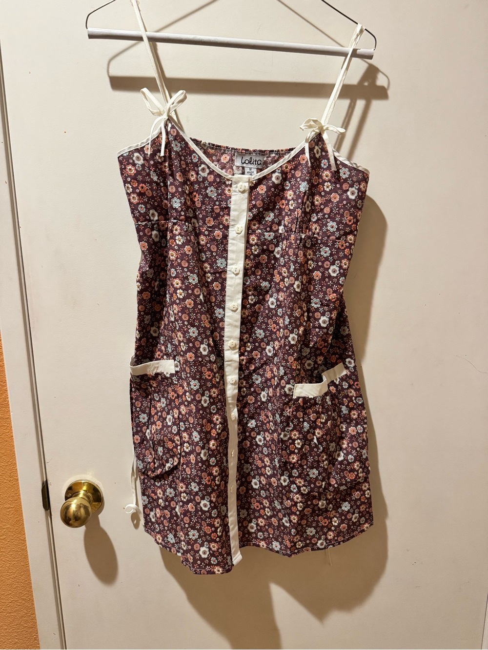 Sleeveless lightweight adjustable shoulder top. Cream button-front placket and
